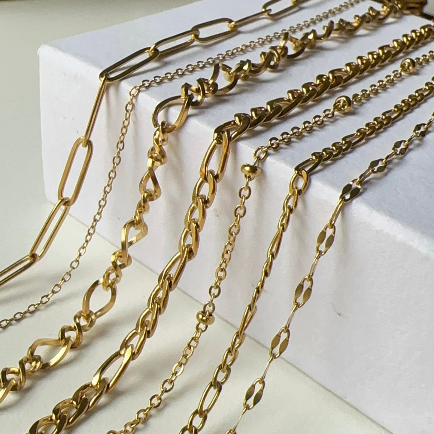 Gold chains of various designs on a white surface